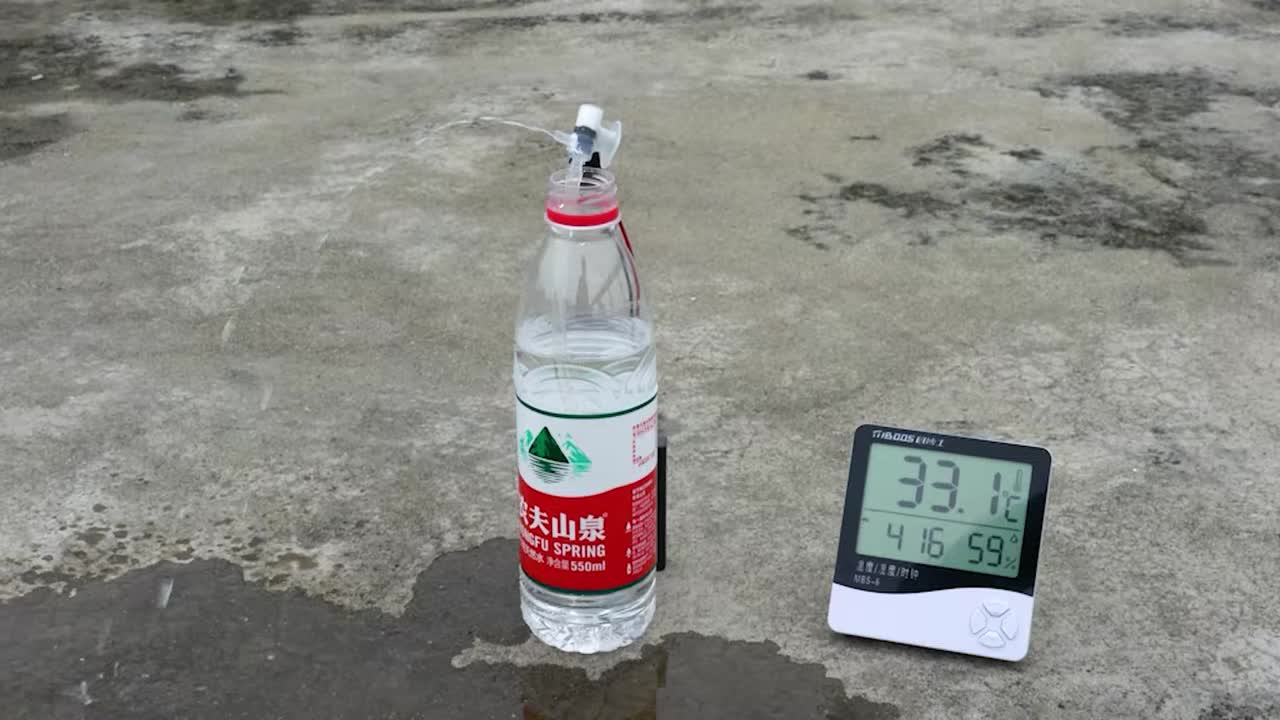 Testing the spray fan attached to a water bottle with a thermometer showing ambient temperature